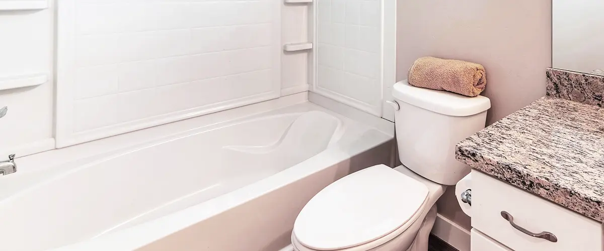 Acrylic bathtub in a modern bathroom with white tiles and granite countertop