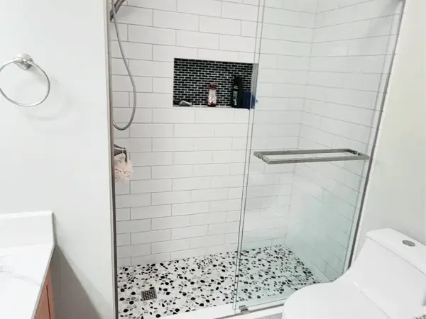 Modern shower with subway tiles, glass door, and decorative niche after tub-to-shower conversion