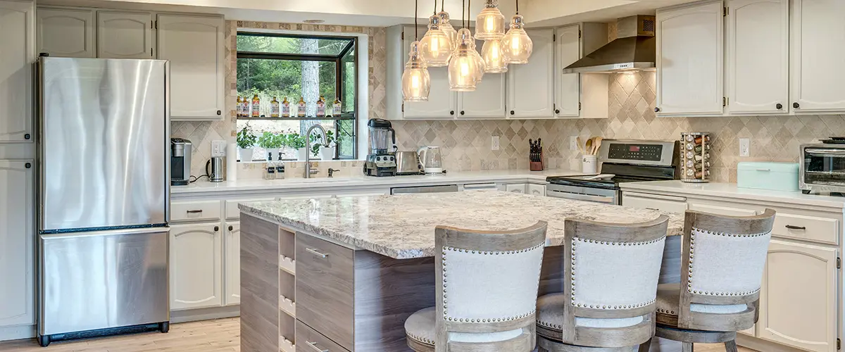 Beautifully remodeled kitchen with a spacious marble island, pendant lighting, and stylish wooden barstools for a cozy ambiance.